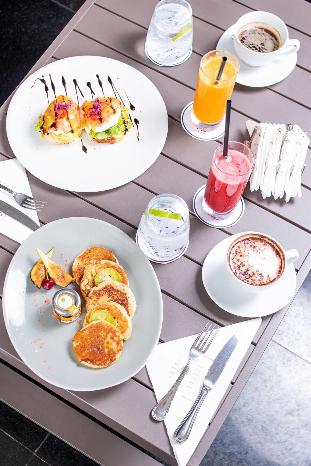 Seen from above: pancakes, eggs with salmon, freshly pressed juices and coffees on the table