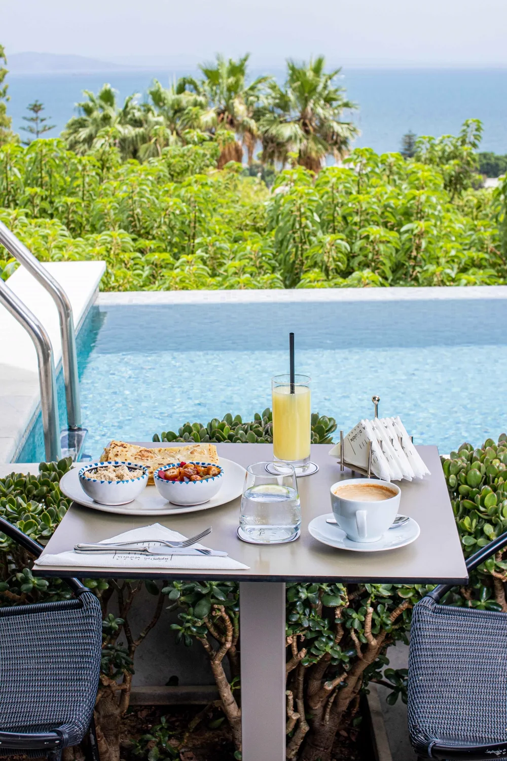The morning table set between the pool and the gardens, the Mediterranean beyond